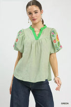 Light green puff-sleeve top with V-neck and floral embroidery on sleeves