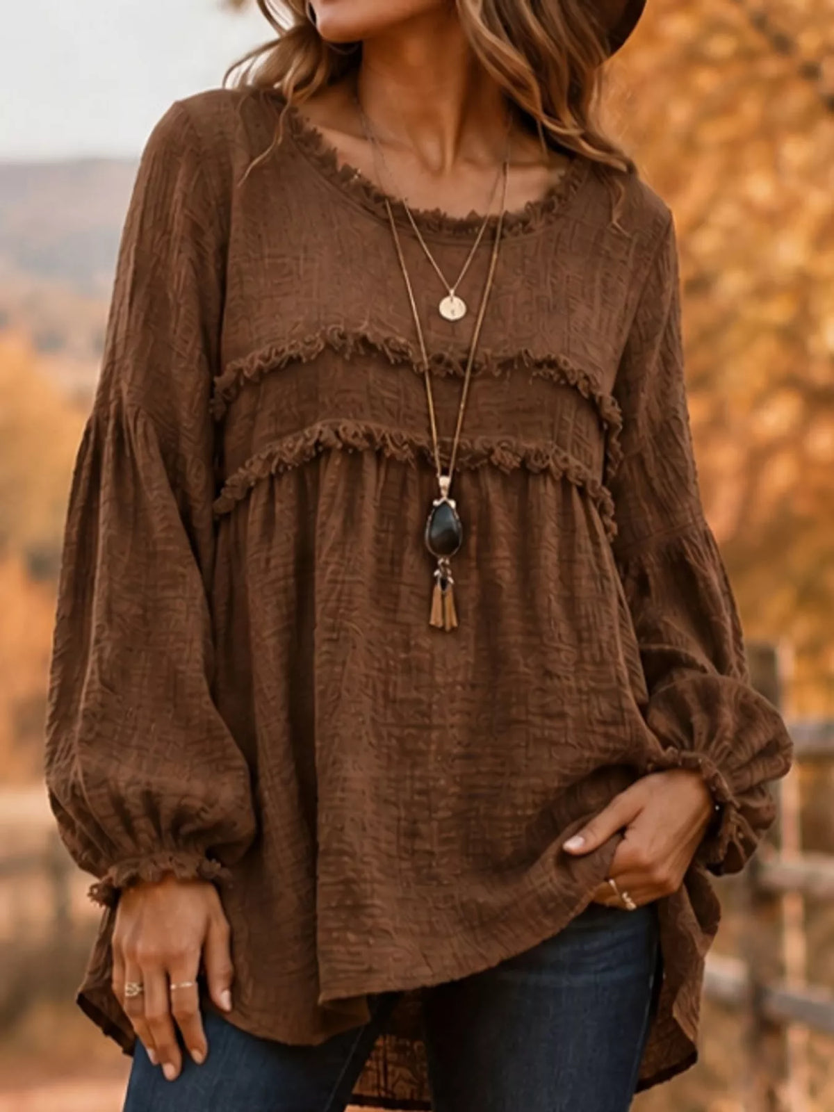Brown peplum blouse with frayed neckline band, long puff sleeves, and tiered ruffles