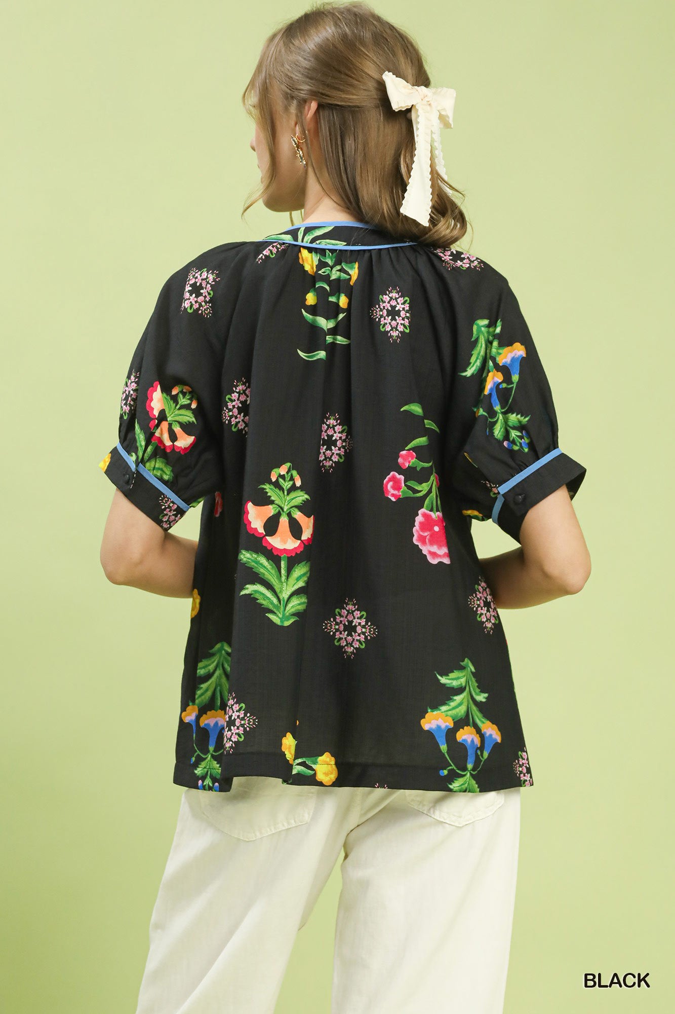 Black botanical print button blouse from the back with blue-trim details and short sleeves