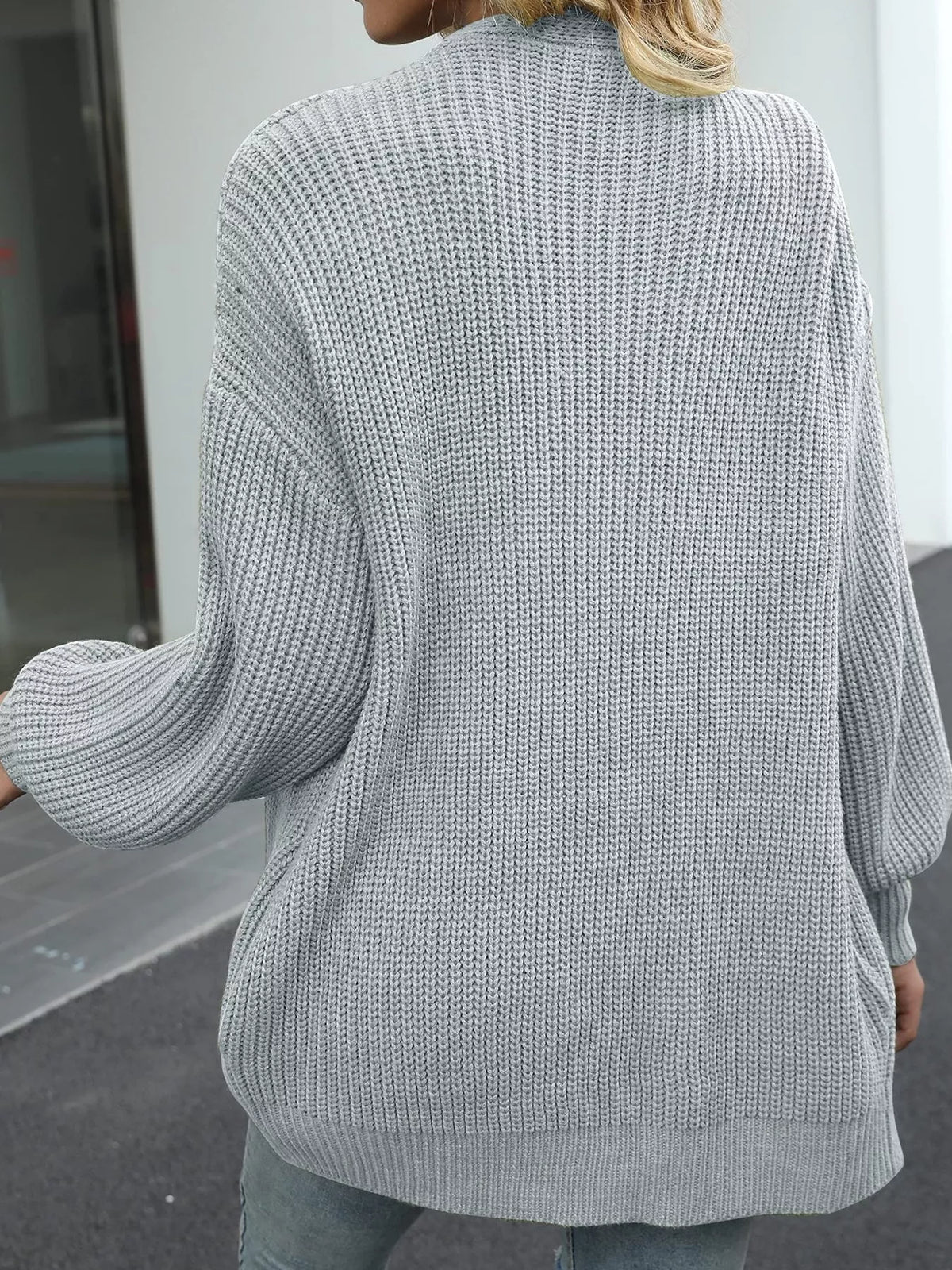 Chunky knit cardigan with lantern sleeves, open back view, light gray color.