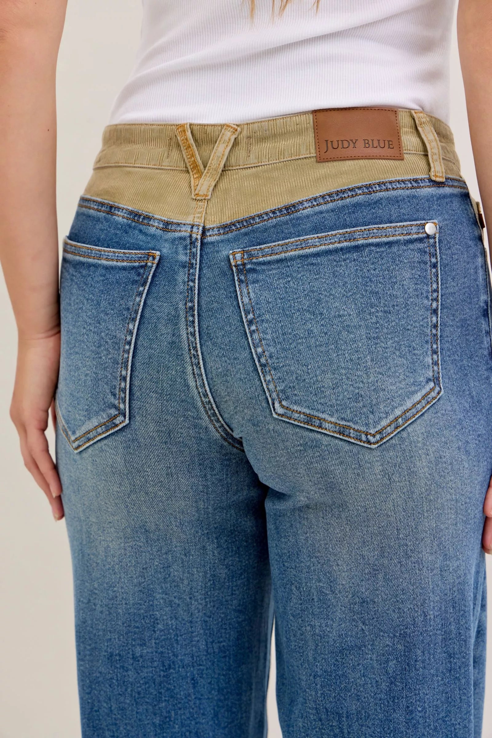 Women’s blue jeans with tan corduroy waistband, button closure and front patch pockets