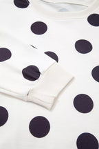 Close-up of sweatshirt cuff and neckline with black polka dots on white knit
