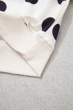 Close-up of sweatshirt hem and sleeve cuff; white knit with black polka dots