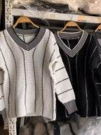 Textured knit V-neck sweaters on hangers: light cream and black with contrast trim.