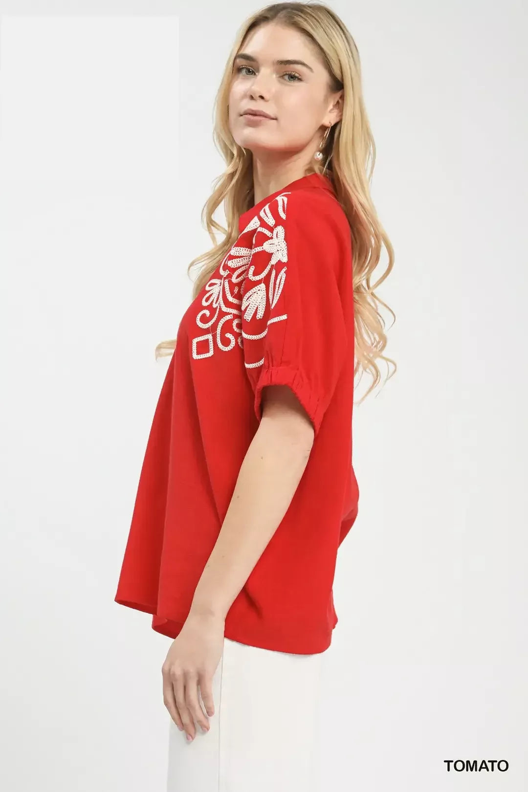 Red blouse side view with white floral embroidery on the sleeve.