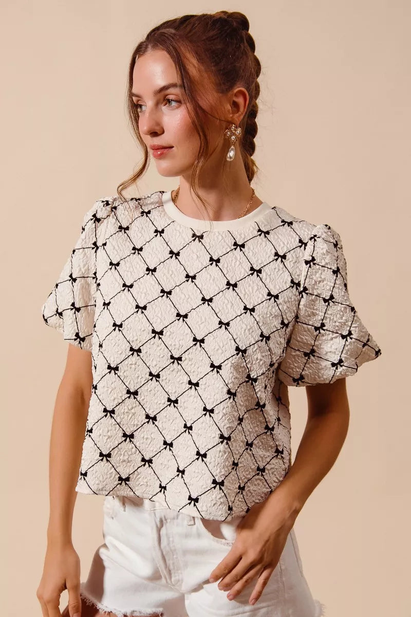 Ivory textured woven top with black bow pattern, short puff bubble sleeves