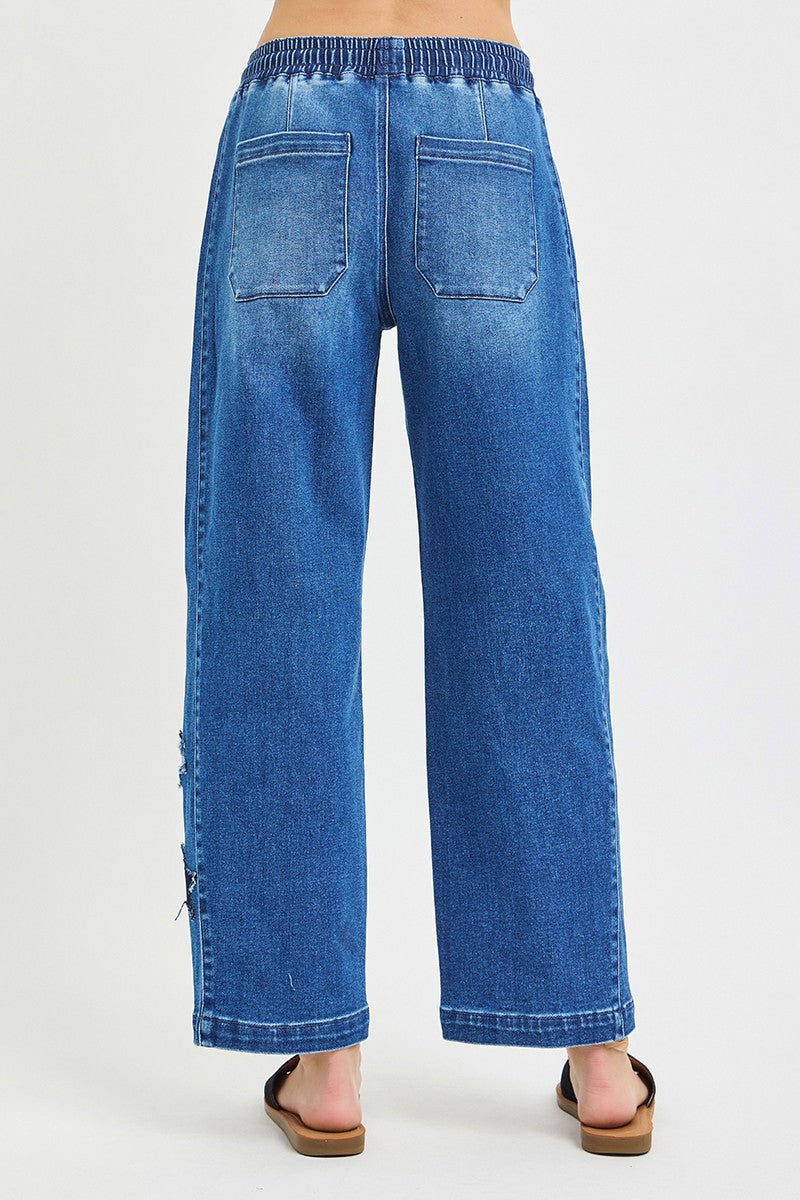 Back view of medium-wash cropped barrel jeans with elastic waistband and relaxed leg shape