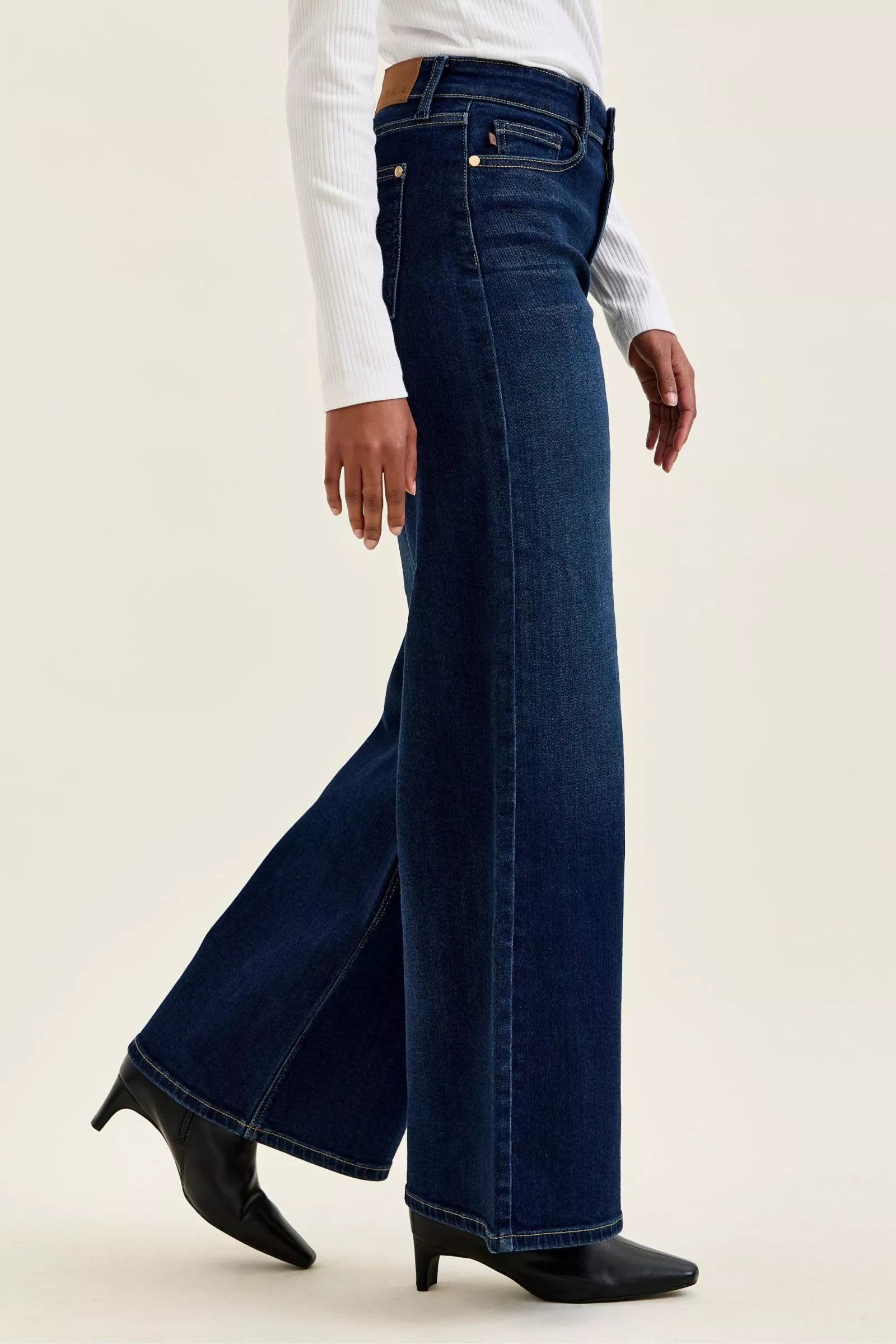 Dark wash wide-leg jeans in profile with flared hem and visible seam stitching