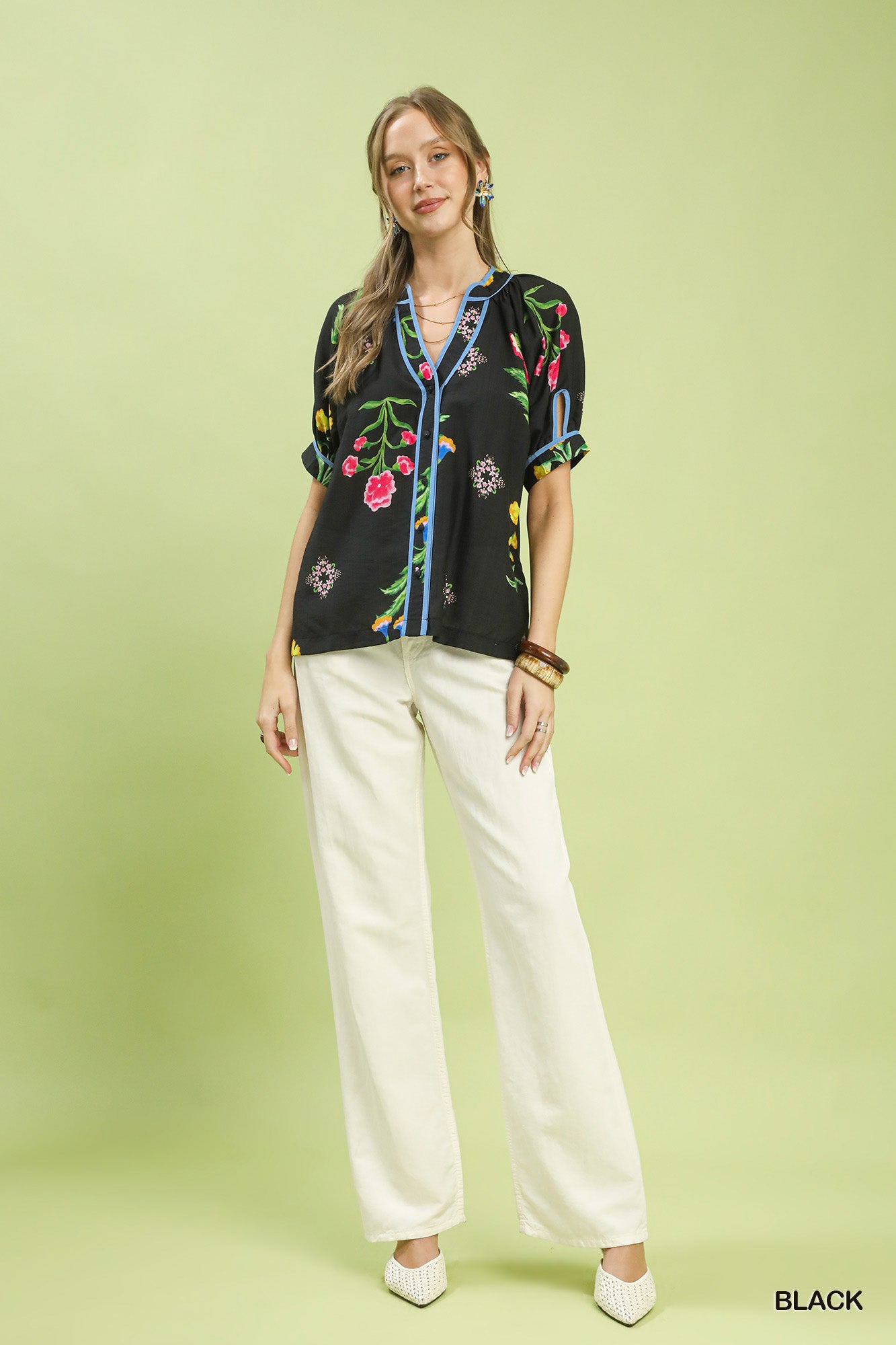 Black botanical print button blouse with colorful flowers, blue trim, styled with white pants