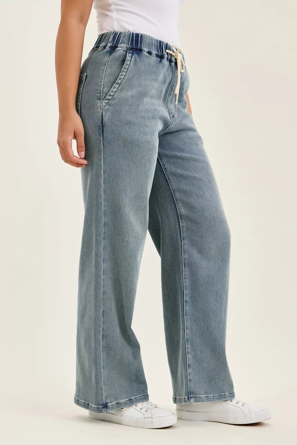 Medium-wash baggy jeans, side view with patch pockets and stitched seams