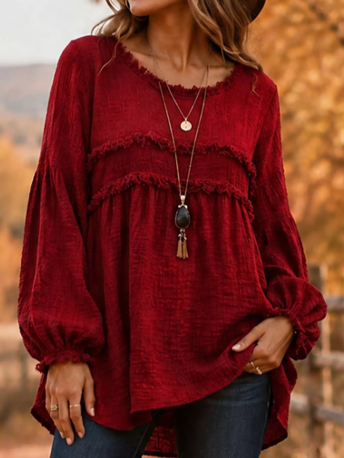 Red peplum blouse with frayed yoke trim, long balloon sleeves, and rounded neckline