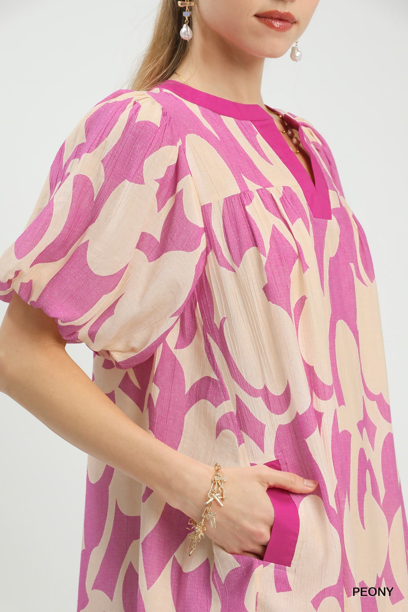 Pink and cream patterned mini dress close-up: V-neck and puff sleeve