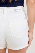 White denim shorts close-up: logo patch at waistband and front pocket detail.