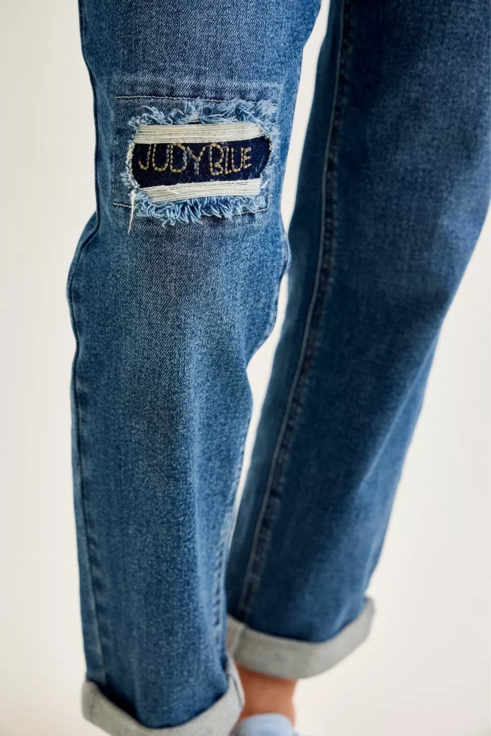 Embroidered denim repair patch on the leg of women’s boyfriend jeans
