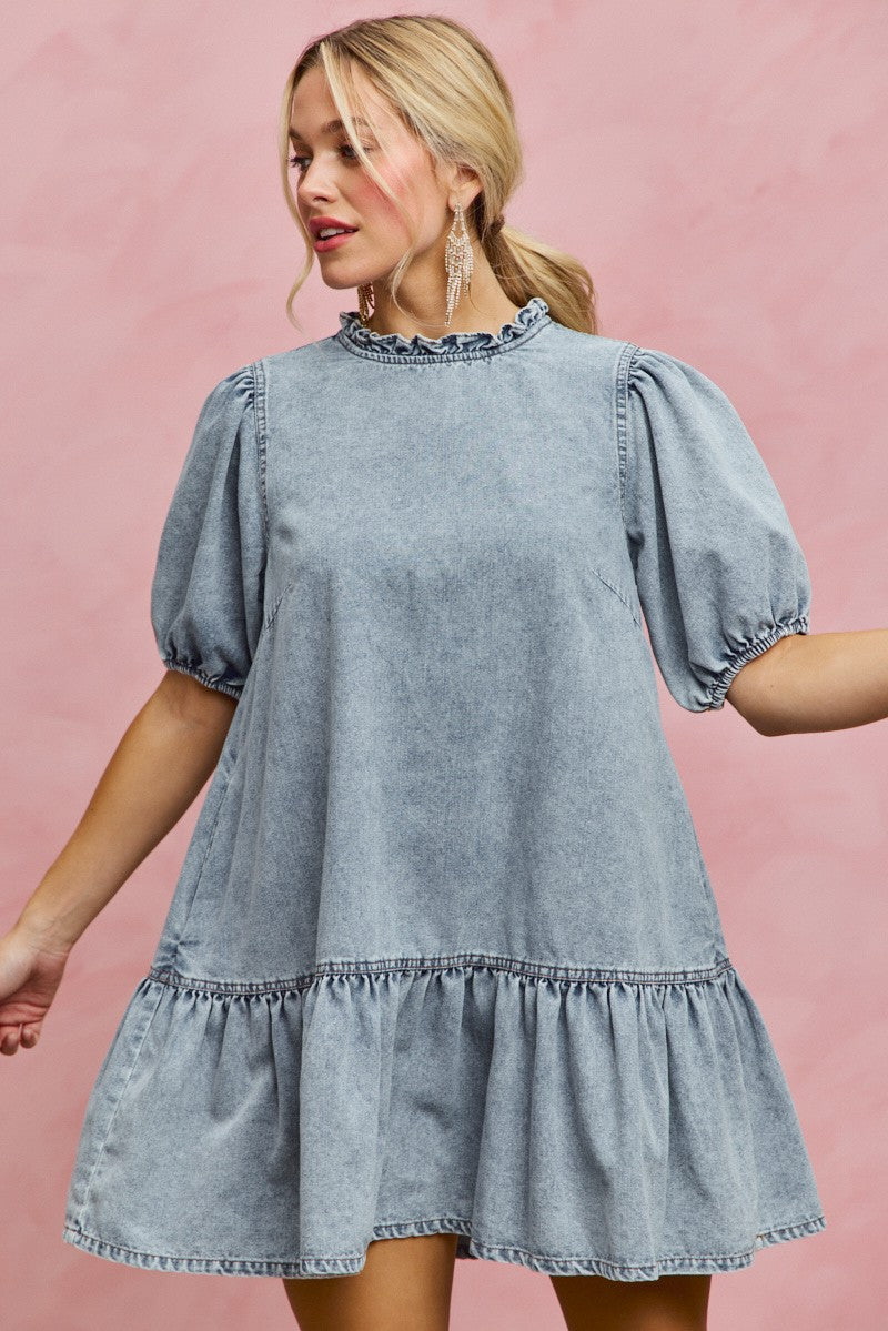 Light wash denim mini dress with ruffled neckline, puff sleeves, and gathered tiered hem