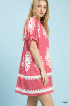 Pink mini dress with white floral border print, puff sleeves, and ruffle trim