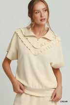 Cream ruffle-collar quarter-zip short-sleeve top with decorative trim at neckline