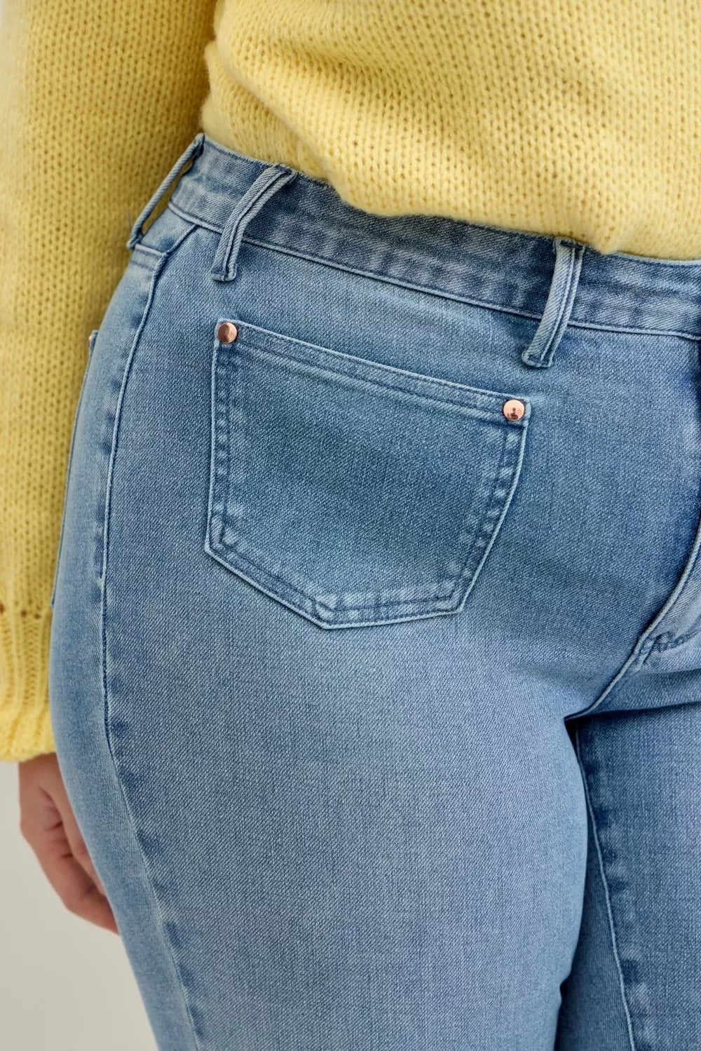 Light blue jeans close-up with button fly, front patch pocket, and belt loops