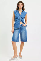 Medium-wash denim jorts with raw hem worn with a sleeveless denim top