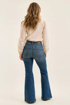 High-waist flare jeans in blue denim, back view showing belt loops and wide leg opening