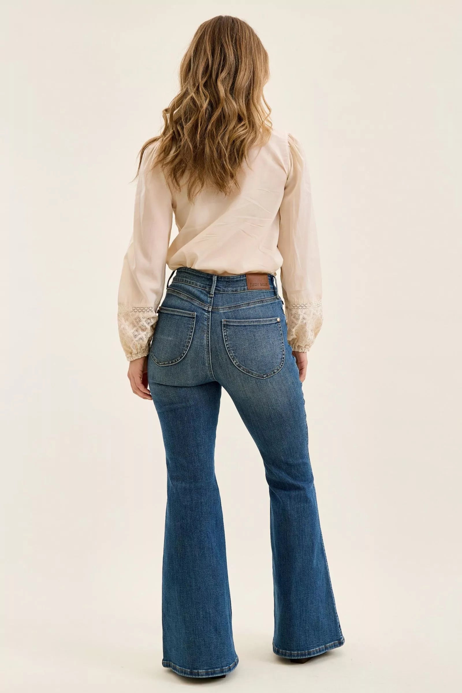 High-waist flare jeans in blue denim, back view showing belt loops and wide leg opening