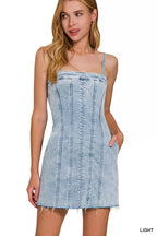 Light wash denim spaghetti strap dress with square neckline and exposed seams, frayed hem