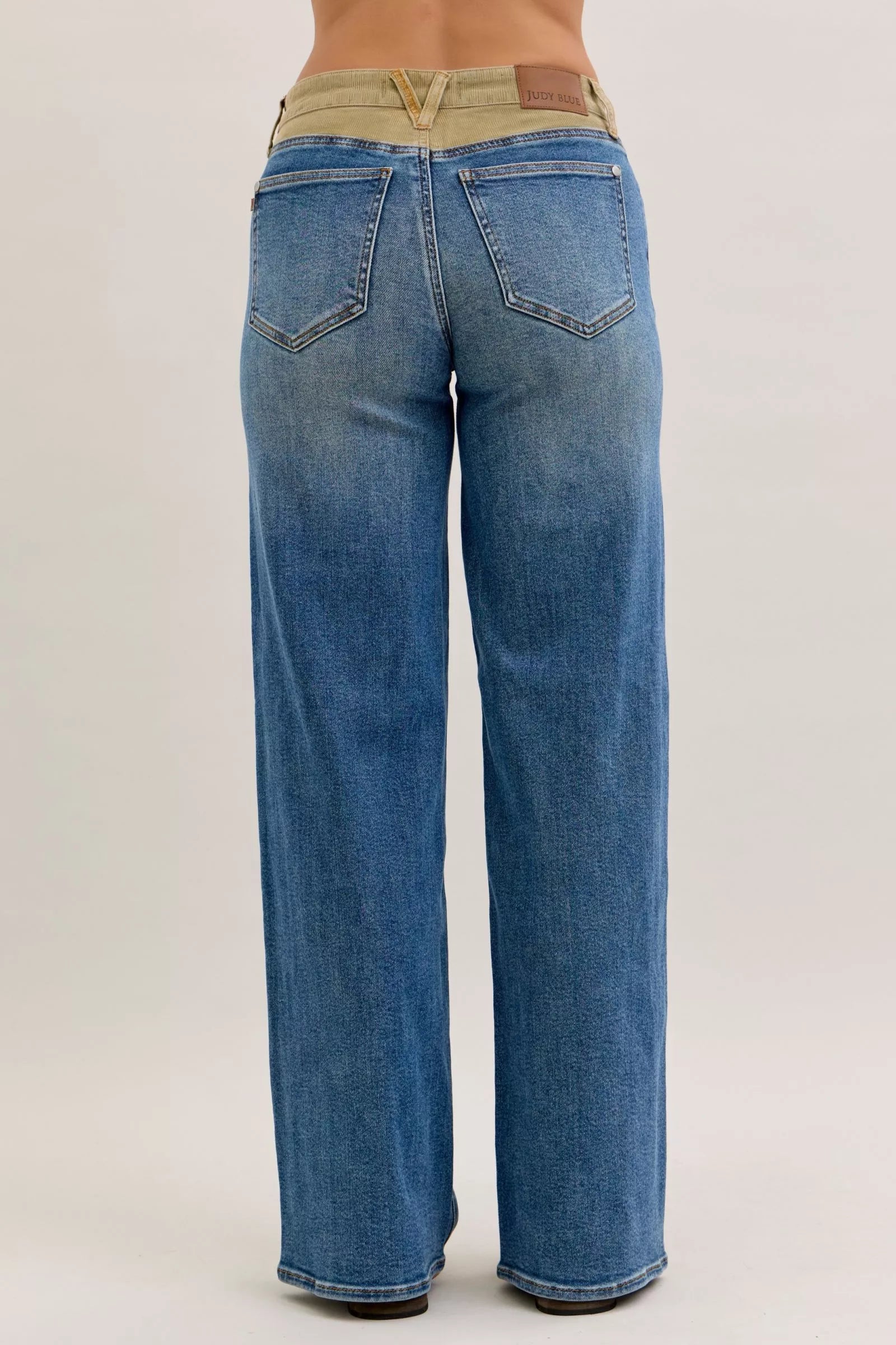 Women’s mid-rise straight jeans with blue denim and tan corduroy waistband, rear view