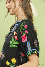 Black botanical print blouse with blue trim and short cuff sleeves, side view