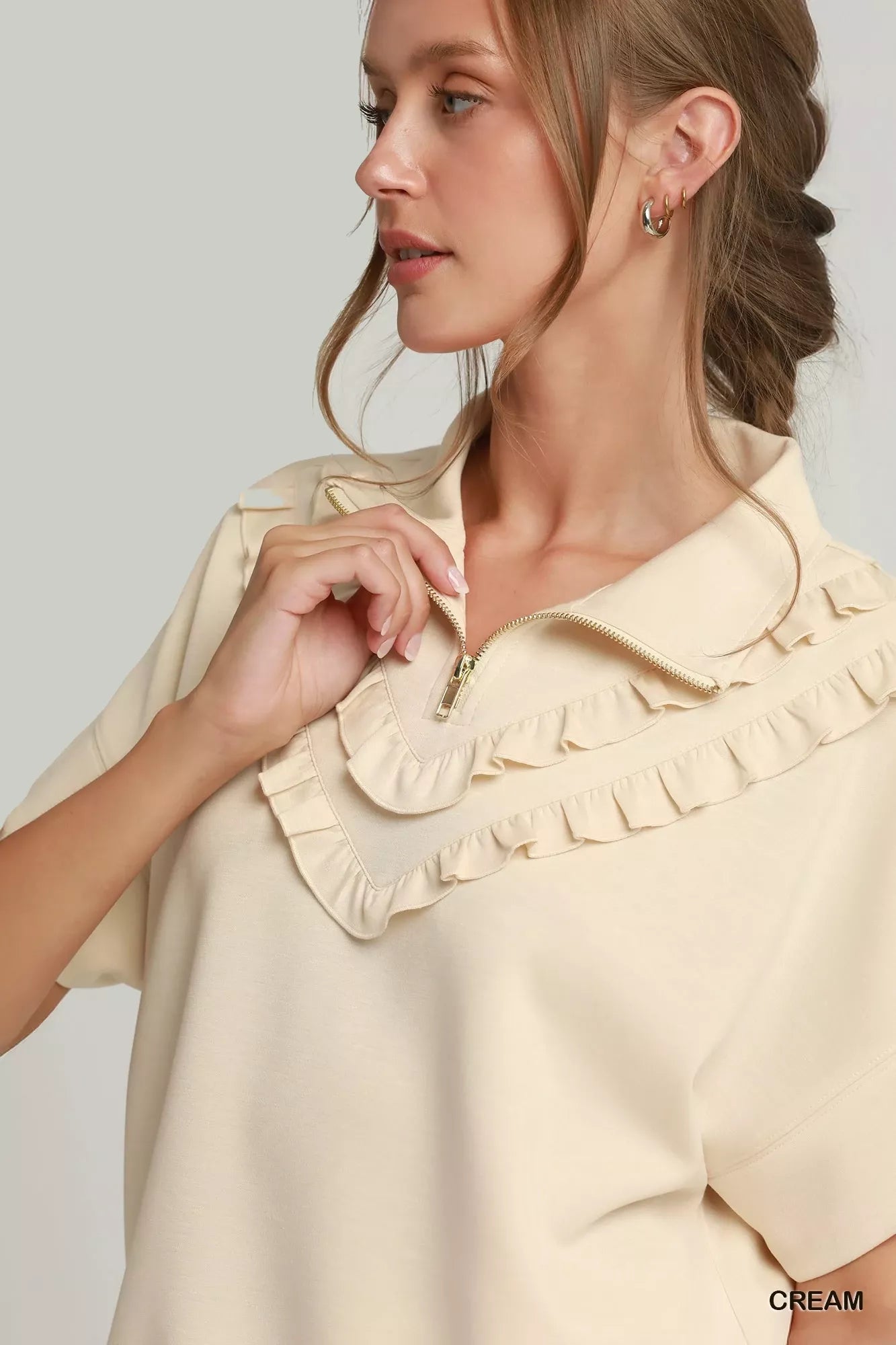 Cream quarter-zip short-sleeve top with ruffled collar and zipper front detail