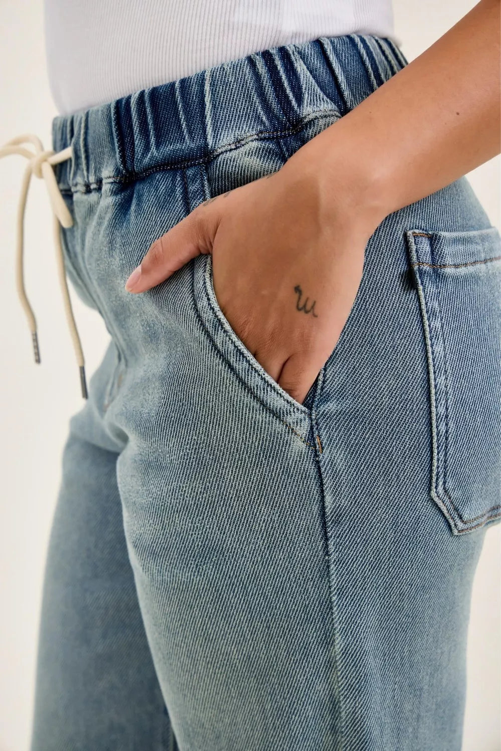 Medium-wash denim with drawstring elastic waist and front V-shaped seam detail