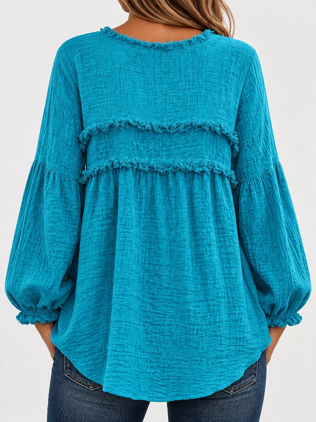 Back view of teal peplum blouse with frayed trim and gathered balloon sleeves