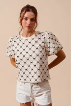 Ivory textured woven top with black bow pattern and puff bubble sleeves