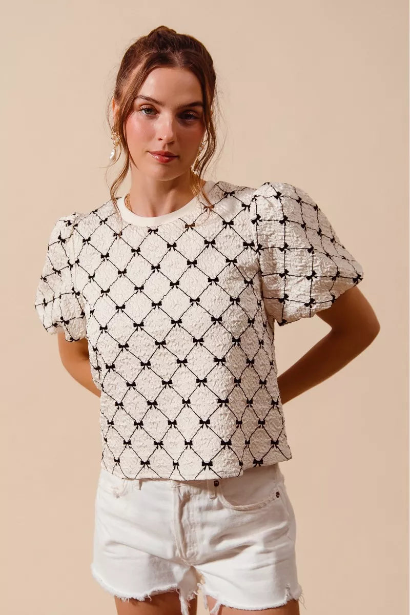 Ivory textured woven top with black bow pattern and puff bubble sleeves