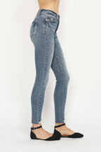 Medium wash skinny jeans with whiskered thighs, front pockets, button-zip closure.