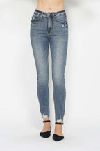 Medium wash skinny jeans with destroyed ankle hem, five-pocket design, button-zip closure.