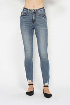Medium wash skinny jeans with frayed ankle hem and front coin pocket, button-zip closure.