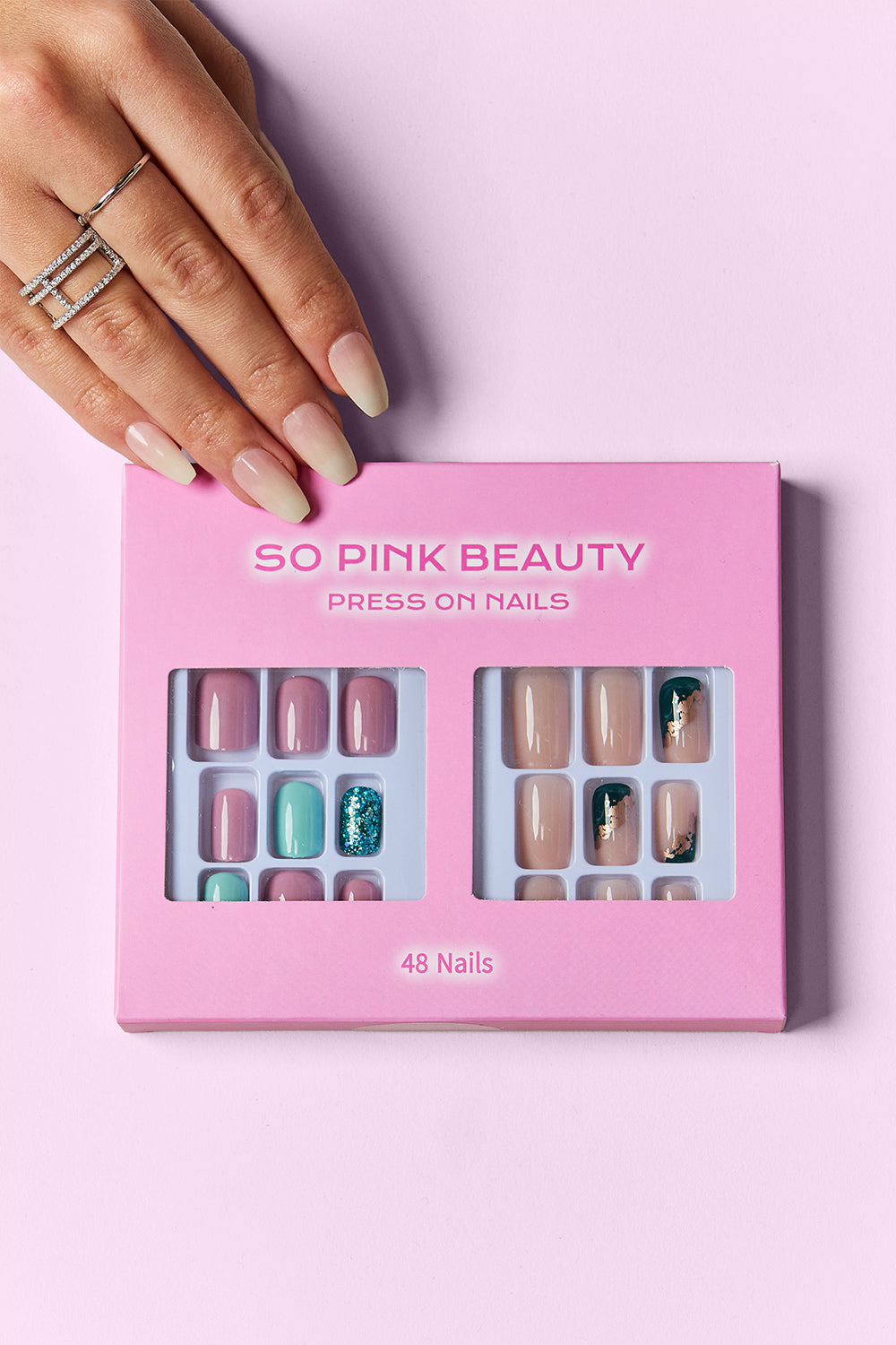 Press-on nail set in pink display box, with mauve, nude, and teal glitter designs