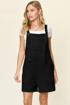 Black textured sleeveless romper with square neckline and button straps, above-knee length